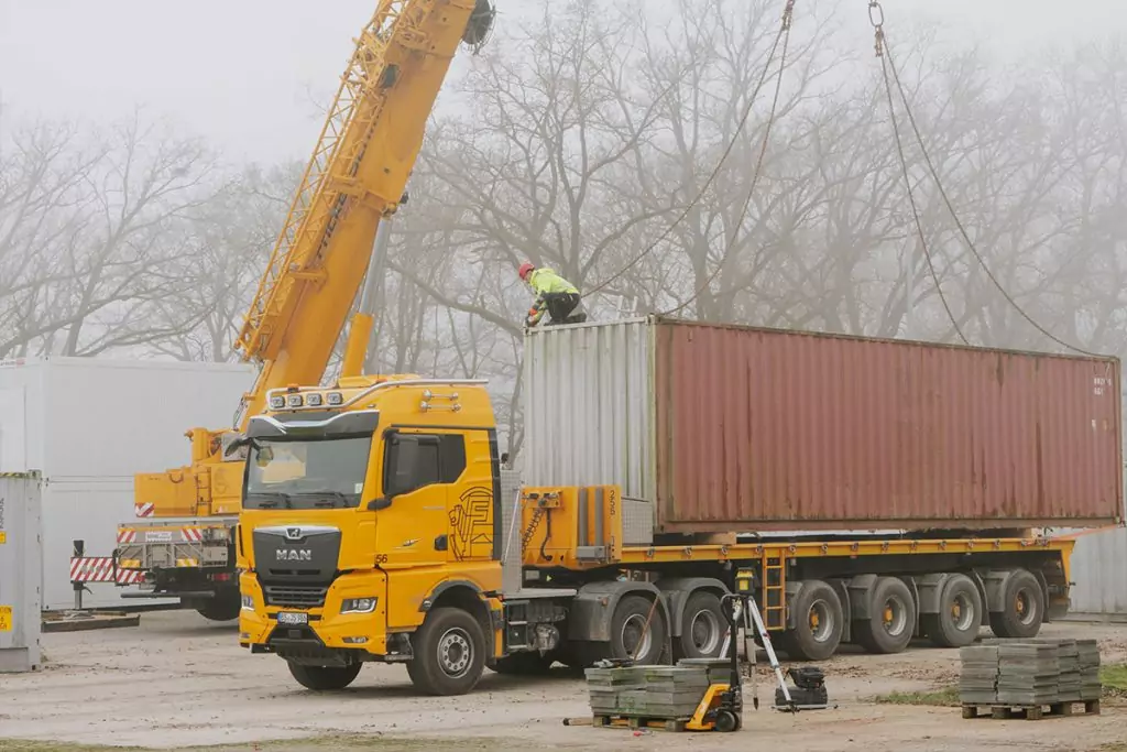 Mobilkran neben einem Lkw mit Container